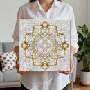 Person holding a decorative wall art piece with a geometric pattern in a living room setting.