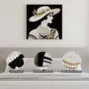 Decorative wall art of a woman with pearls and a hat, displayed on a wall above a sofa.
