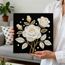 Person holding a black square with white and gold floral design in a living room setting.
