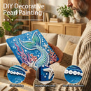 Person holding a DIY decorative pearl painting with mermaid design in a living room.