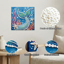 Decorative wall art with mermaid design and pearl embellishments, shown on a wall with a sofa and table.