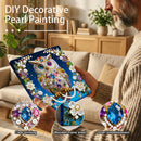 Person holding a DIY decorative pearl painting kit with an owl design, set against a home interior background.