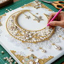 Handmade jewelry design with pearls and gold accents on a white card, with a hand holding a pink pen.