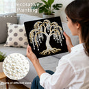Woman holding a decorative pearl painting of a tree, with pearls of different sizes shown.