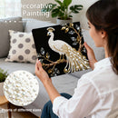 Woman holding a decorative item with peacock design and pearls, surrounded by a cozy living room setting.