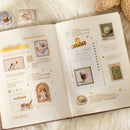 Open book with decorative pages featuring illustrations of cats and coffee on a soft surface.