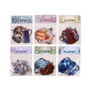 Packaged teapot-shaped items with decorative designs on clear plastic packaging.
