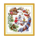 Cross-stitched scene with children making a snowman, framed in gold.