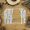 Metal tree-shaped cutting die on a wooden surface with natural elements.