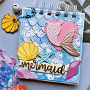 Decorative notebook with mermaid-themed embellishments on a light blue background