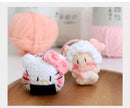 Two plush toys resembling sheep with pink accents on a wooden surface.