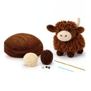 Plush toy Highland cow with yarn balls and knitting needles on a white background