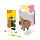 Crochet kit with pre-made animal figure, yarn, hooks, and packaging on a white background