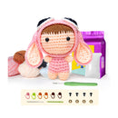 Crocheted doll with pink hood and accessories on a white background