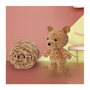 Knitted teddy bear and yarn ball on a pink and yellow background