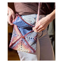Person holding a colorful crocheted bag with a patterned design.