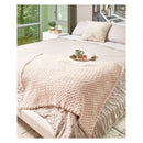 Marshmellow textured throw blanket on a bed in a bedroom with a view of greenery outside.