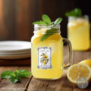 Mason jar with lemonade and mint leaves on a wooden table, with another jar and lemons in the background.