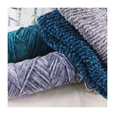 Stack of blue and gray textured yarn balls on a white surface