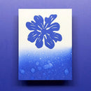 Blue flower design on a white card with blue water droplets, against a purple background
