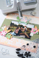 Scrapbooking project with photo, decorative elements, and a printer on a table.