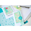 Two handmade cards with floral designs and text, placed on a crafting surface with a die-cutting machine.