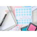 Card with blue snowflakes and text, surrounded by ink pads and a brush on a white background