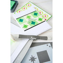 Card with green and red pattern, Sizzix tool, and stencils on a white background