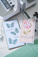 Two greeting cards with butterfly and flower designs on a crafting table.