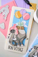 Card with elephant and balloons design, labeled 'Bon Voyage', on a colorful background.