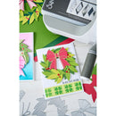 Card with festive design featuring a bow and wreath, surrounded by crafting tools and materials.