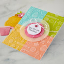 Colorful card with embossed patterns and a tag on a marble surface