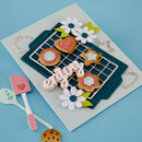 Decorative card with cookies, flowers, and utensils on a blue background