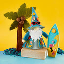 Felt gnome with sunglasses, blue hat, and surfboard next to a palm tree on a yellow and blue background