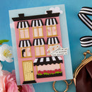 Card with a house design and 'Home is where the heart is' text on a blue background with flowers and a purse.