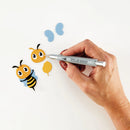 Hand using a small tool to work on bee-shaped stickers with a white background