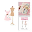 Mannequin with a pink dress, sewing book, and cutting dies on a white background
