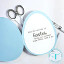Round card with Easter message on a white background with scissors and pen.