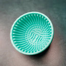 Green silicone strainer on a gray background