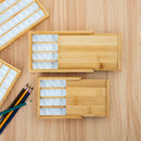 Wooden trays with compartments on a wooden surface with pencils.