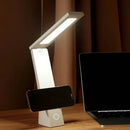 Foldable desk lamp on a table with a laptop and smartphone