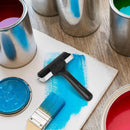 Paint cans with blue and red paint, a paintbrush, and a roller on a wooden surface.