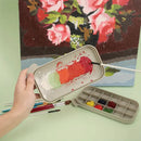 Artistic setup with a small paint palette, brushes, and a painting of flowers in the background.