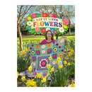 Woman holding a colorful quilt with flowers in a garden, featuring the KING COLE BRAND