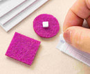 Purple felt squares with a white square in the center on a beige surface.