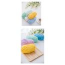 Colorful yarn balls on a white surface with flowers and a cup.
