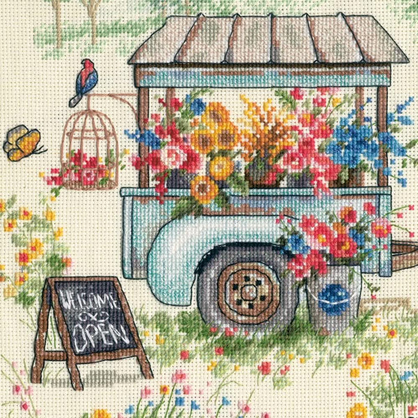 Floral cart with flowers and a 'Welcome Open' sign in a garden setting
