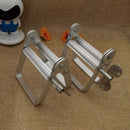 Metal kitchen tool on a textured brown surface with a small figurine and flowers in the background.
