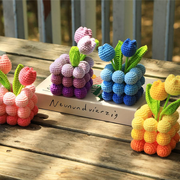 Colorful crocheted berry and flower decorations on a wooden surface with 'Neunundvierzig' branding.