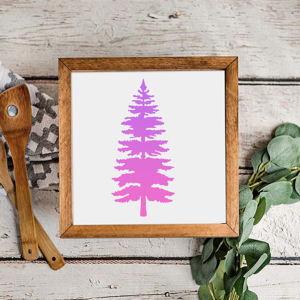 Framed artwork with a pink tree design on a wooden surface with kitchen utensils and greenery.